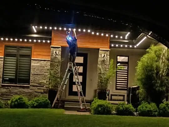 Outdoor LED lighting being installed from a ladder at night